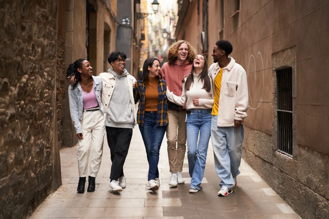 Group of young happy friends walking in the street of the city. Smiling students laughing