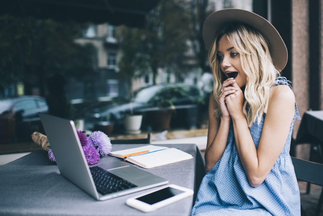 Surprised hipster girl with expression on face feeling excited while watching video vlog